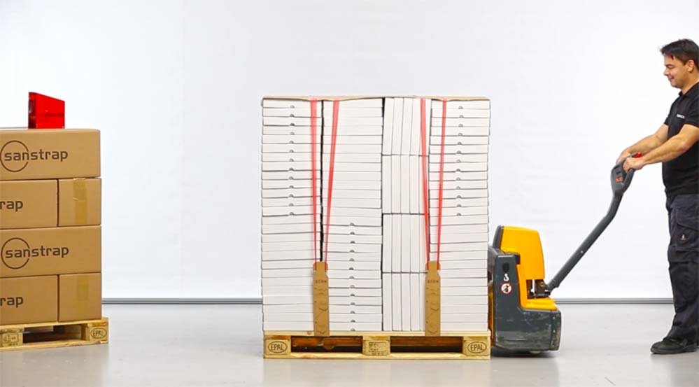 Mitarbeiter zieht Palette mit 2Link® und sanstrap®-gesichertem Packgut per Hubwagen
